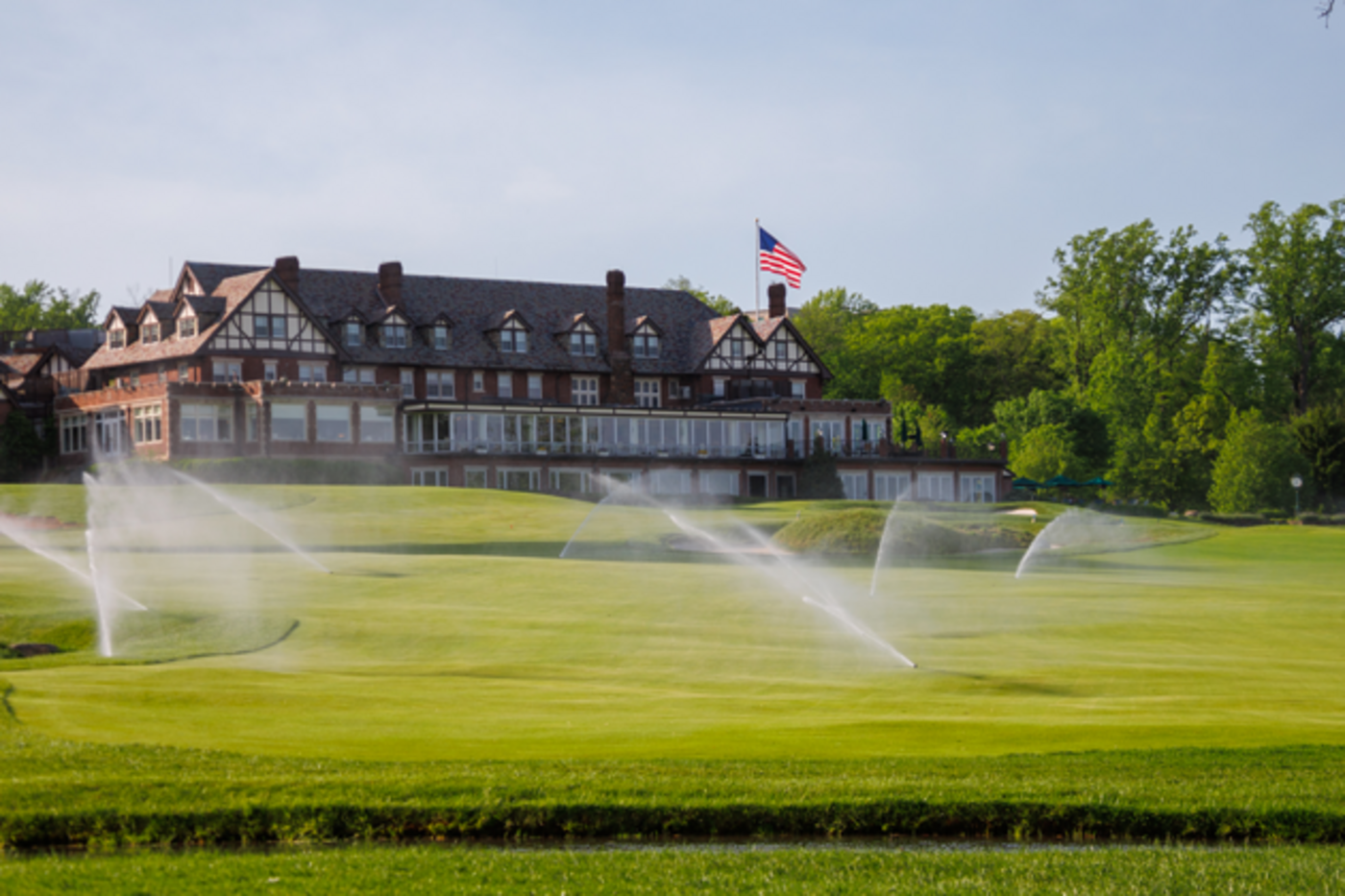 Golf course with sprinklers watering the grass and building in background